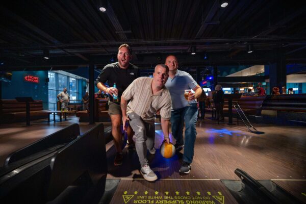 Allstars Sports bowling event at Weston — three men celebrating at a bowling alley